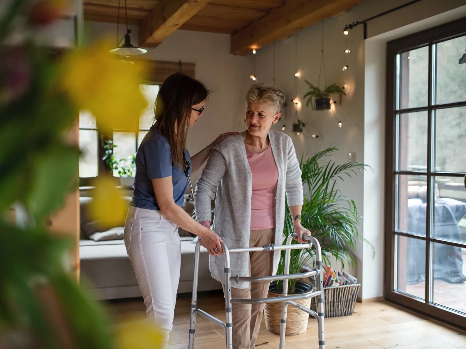 Care worker helping an older woman practise walking at home