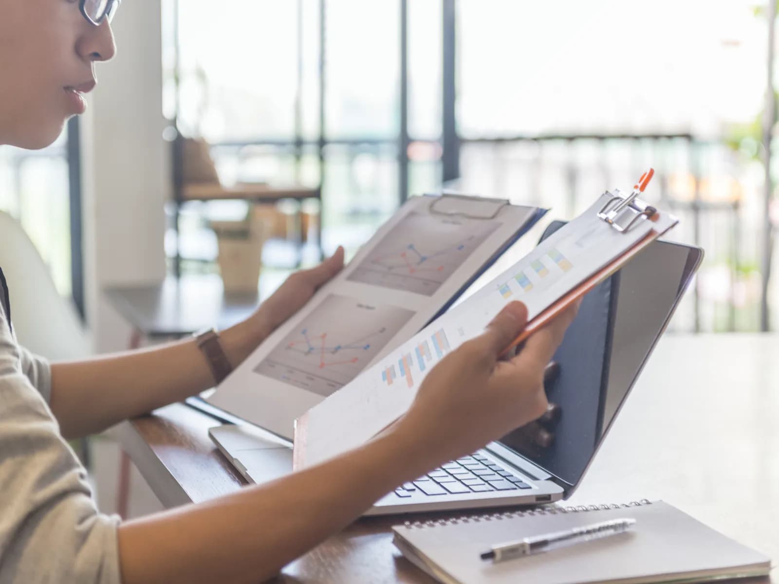 A business owner reviewing financial documents beside a laptop.