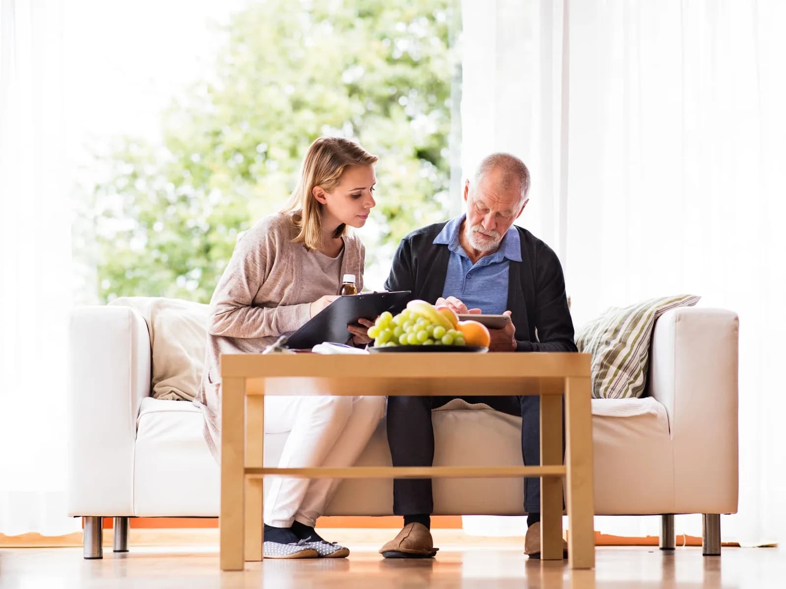 Care worker reviewing notes on a tablet with an older client