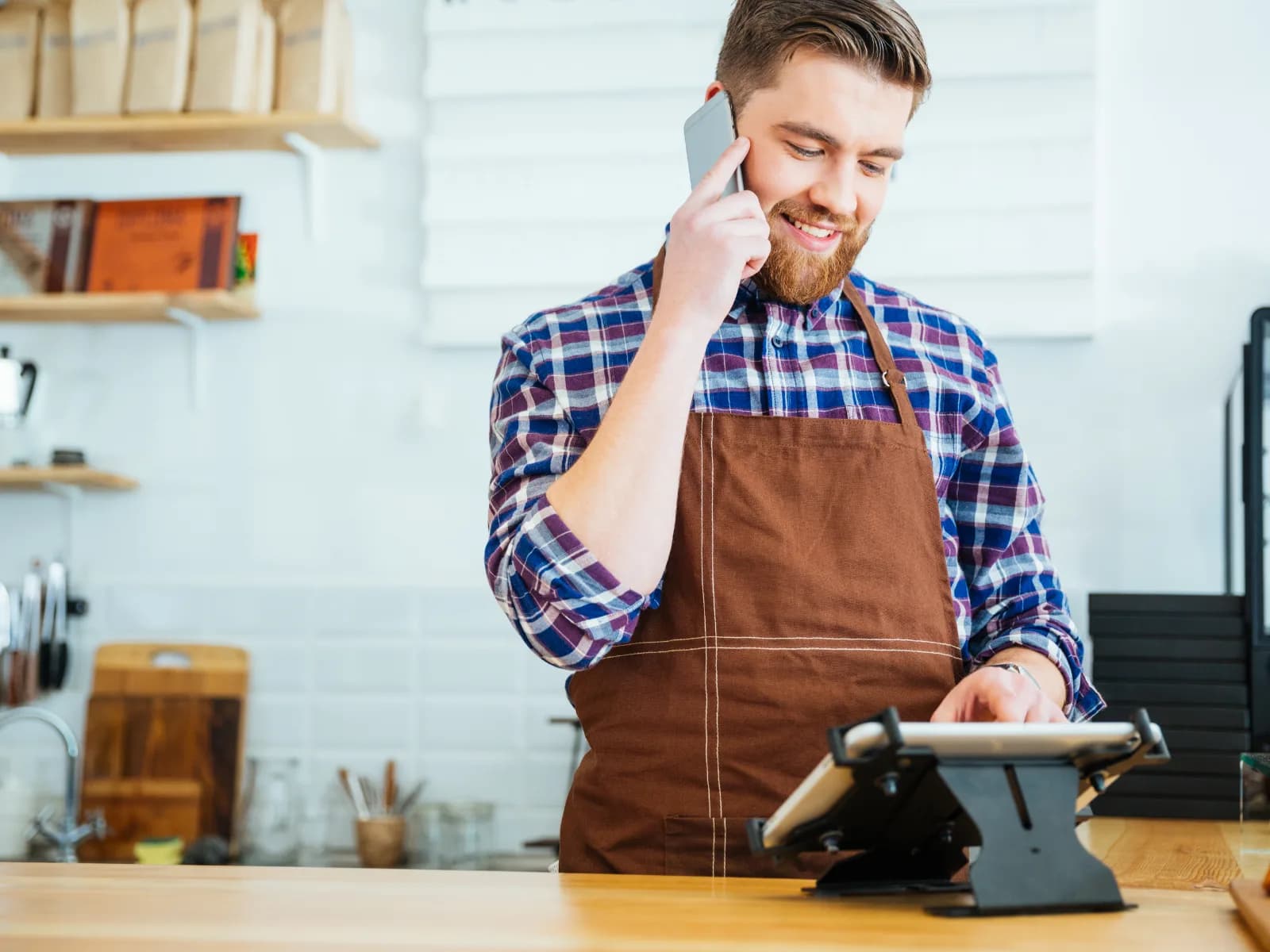Barista using a phone and tablet in a café.