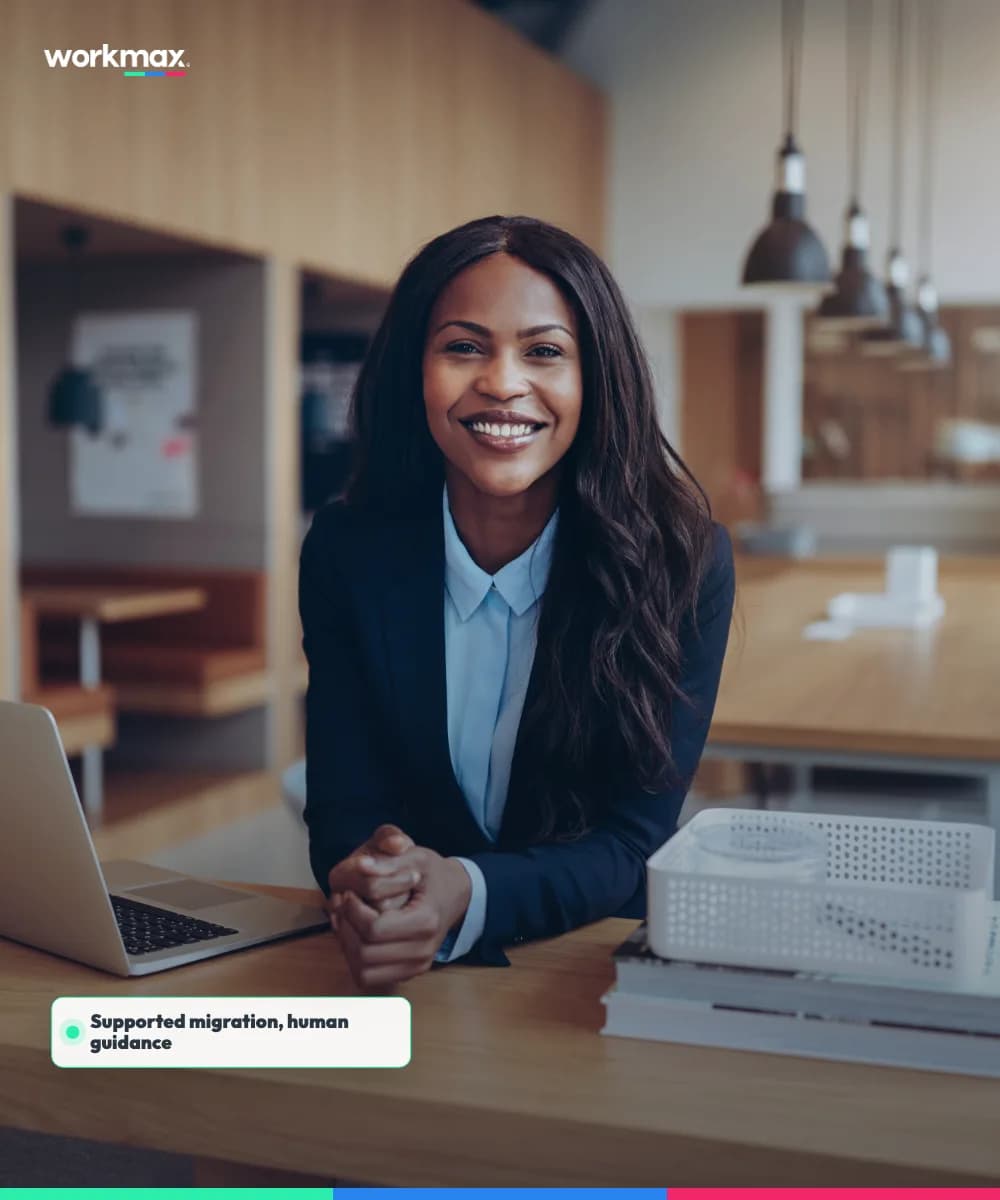 Office professional smiling beside a laptop in a bright modern workplace.